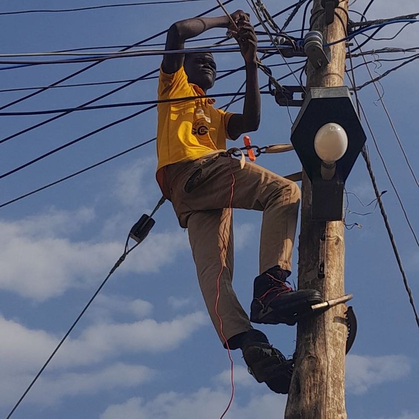 A student working on overhead lines at the top of a pole