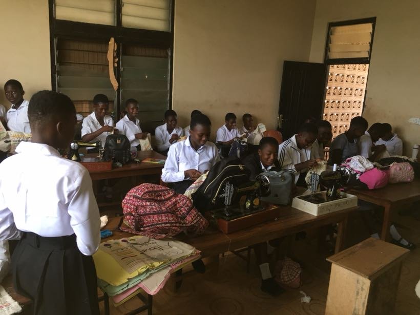 A busy classroom of students working at sewing machines