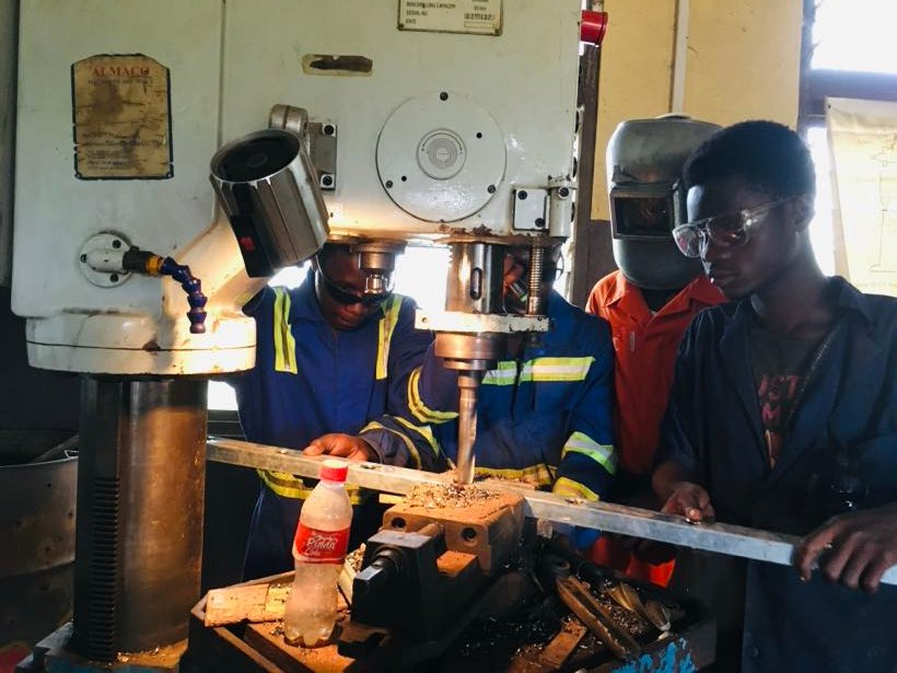 Students operating a pillar drill in the mechanical workshop