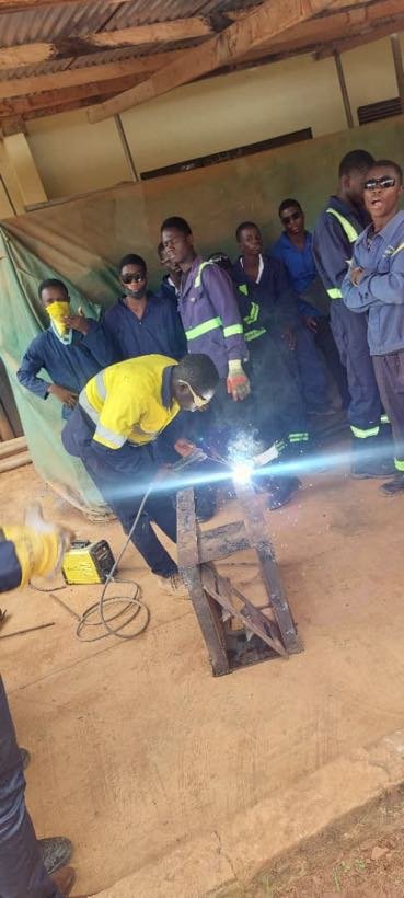 A student welding while classmates look on